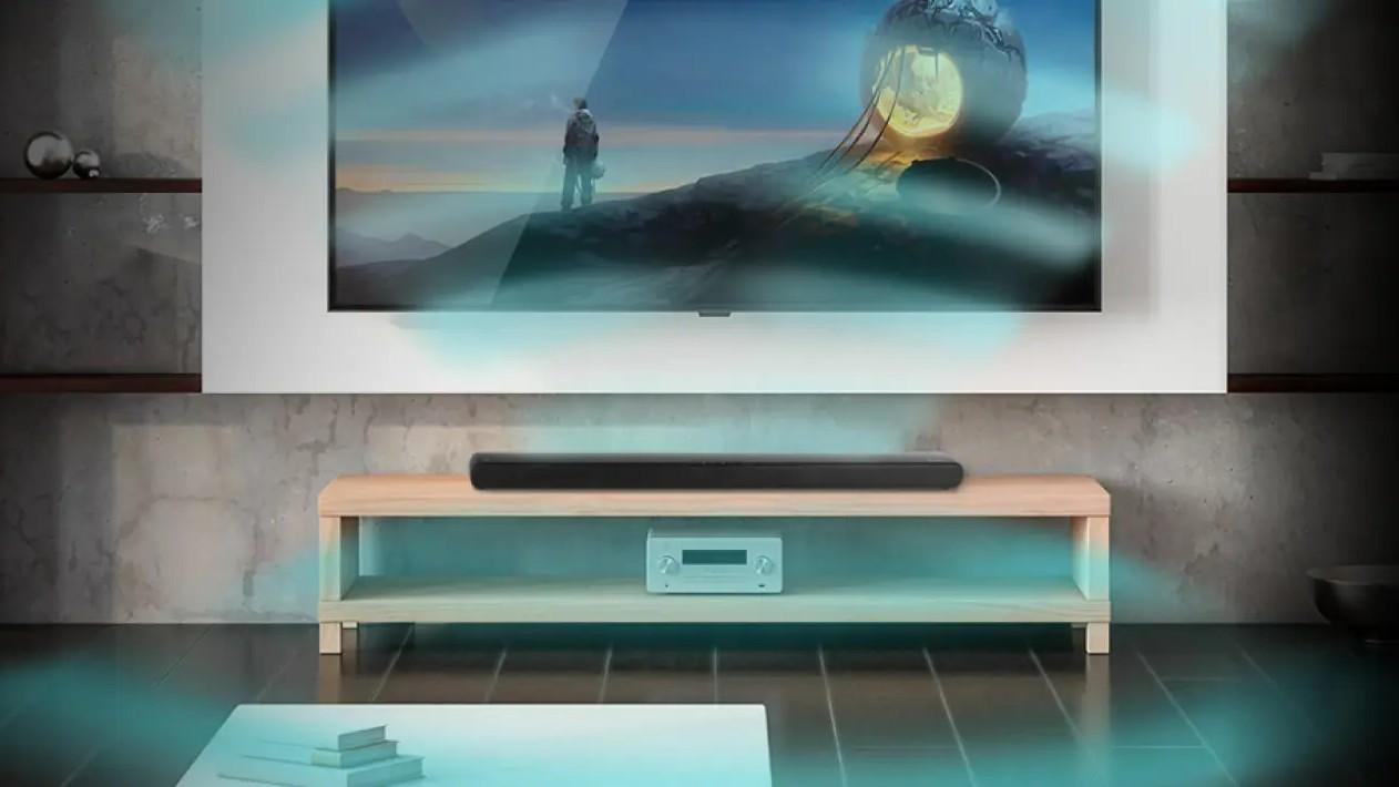 The black Monoprice SB-300 soundbar sits on a TV console with simulated dolby atmos emulating from it in teal waves.