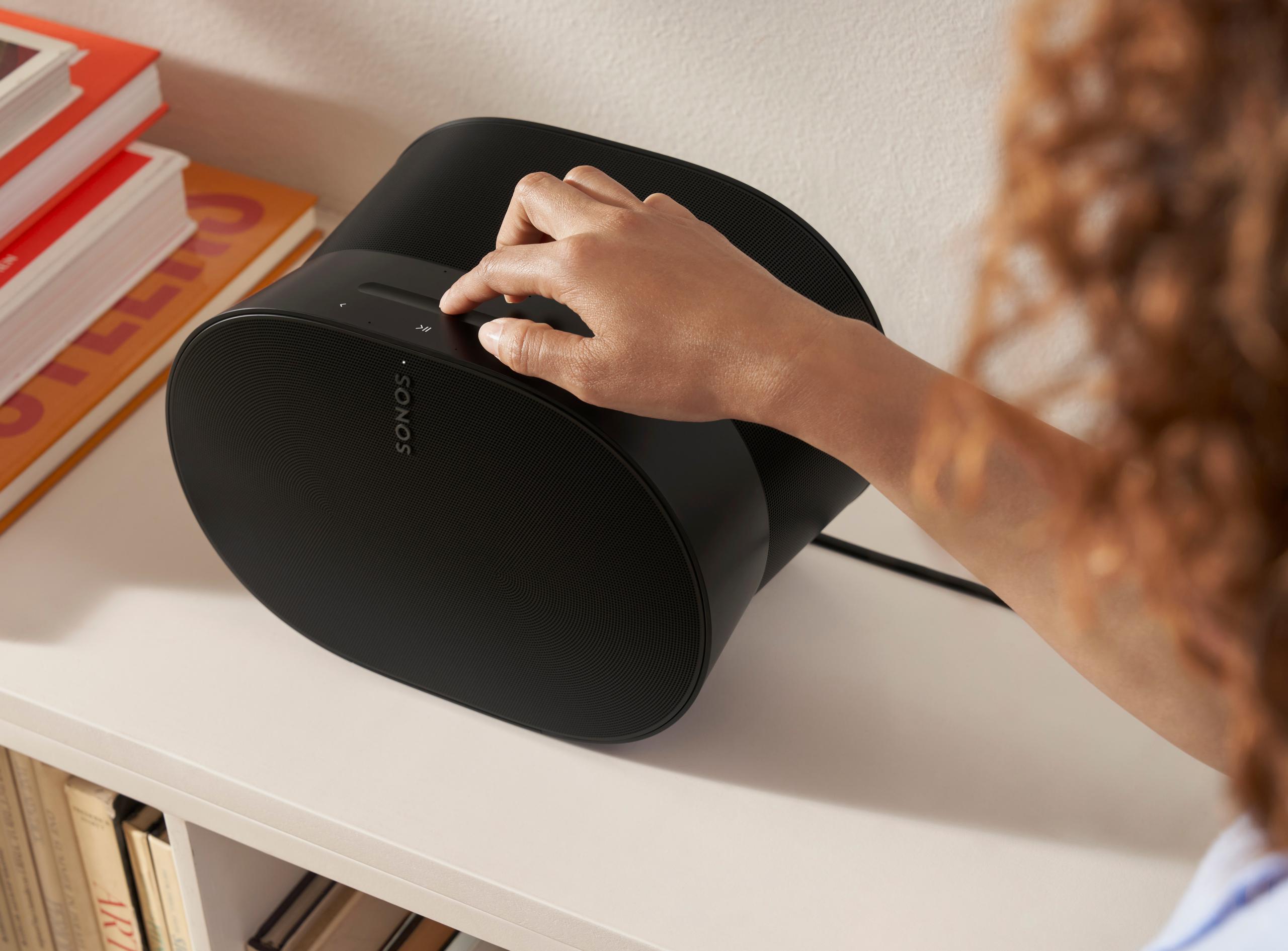 A person uses the touch control volume slider on a Sonos Era 300 smart speaker.