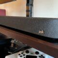 The Polk Magnifi Max soundbar is shown from the right side on a black and brown TV console.