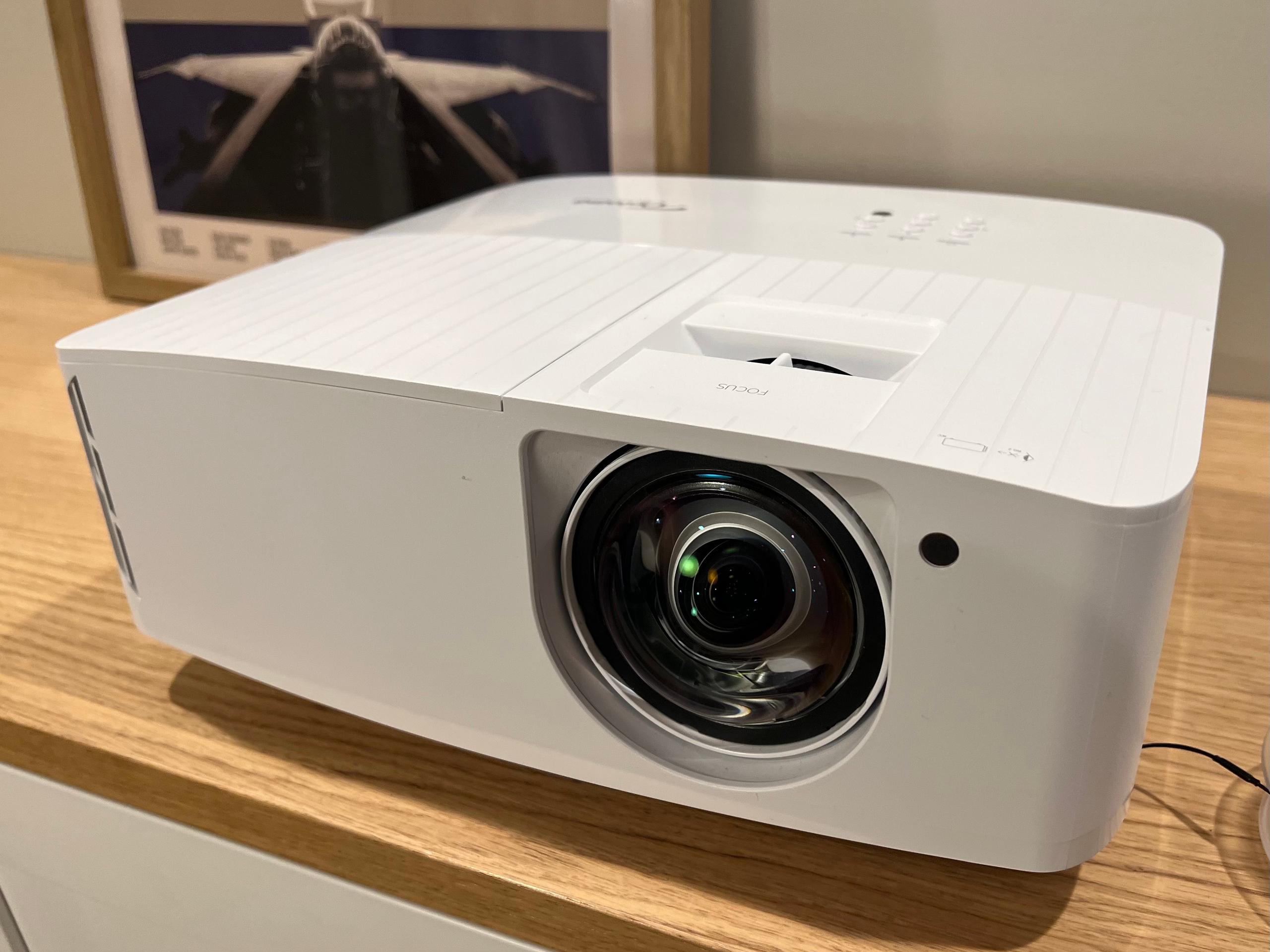 The Optoma UHD35stx 4K projector is shown from the right on a table.