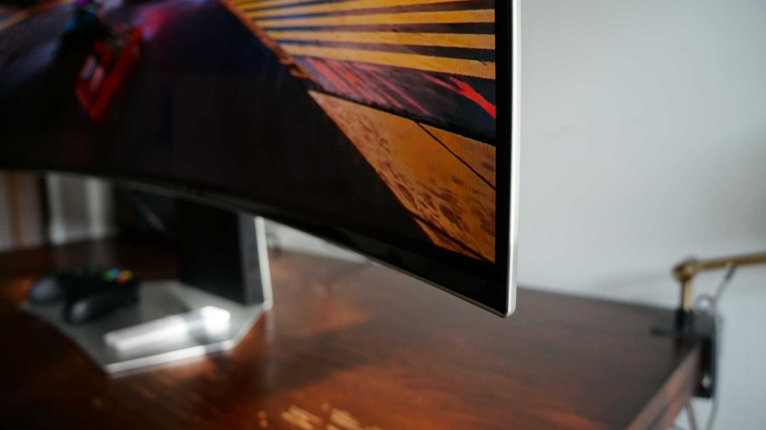 Edge of a Samsung Odyssey OLED G9 monitor on a brown desk