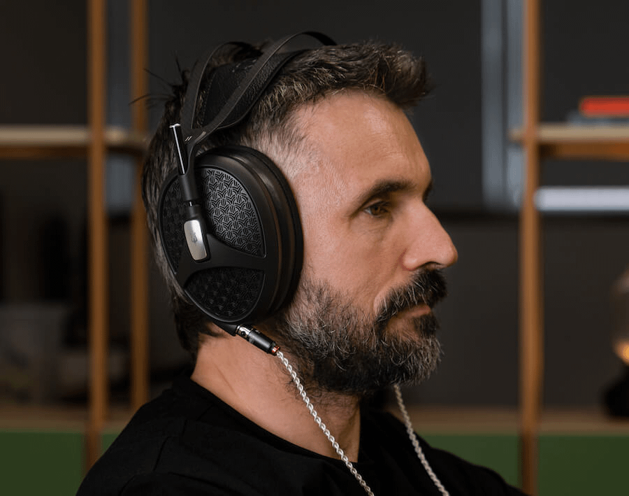 A man wearing Meze Audio Empyrean II headphones, profile view.