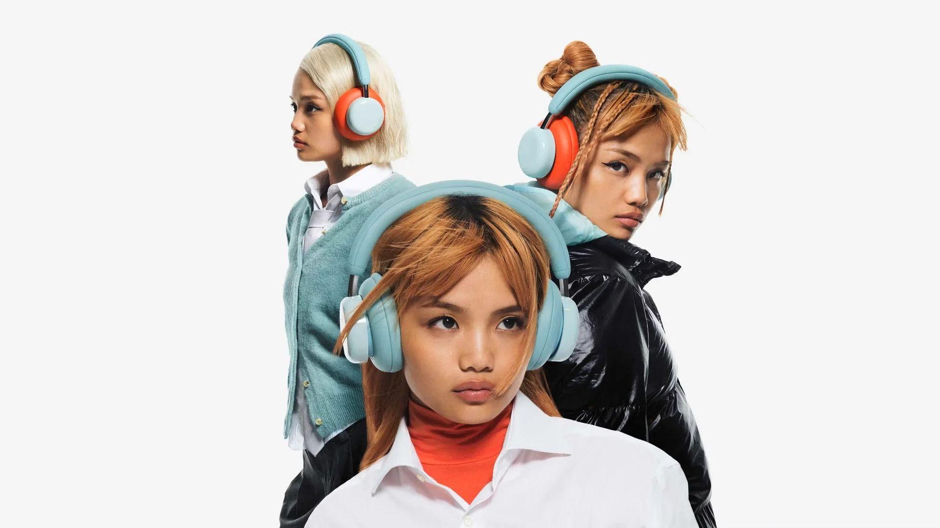 Three young women wearing CMF Headphone Pro headphones.