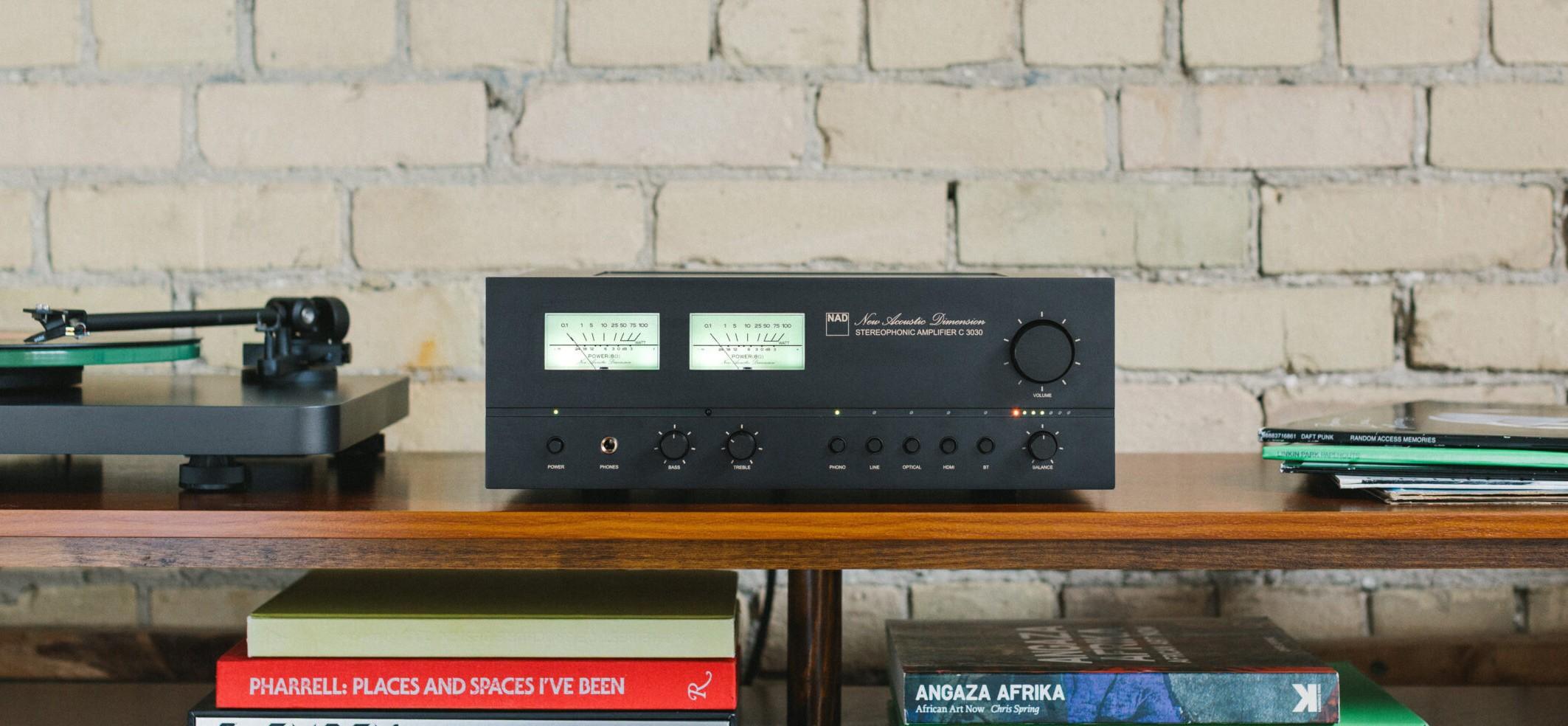 NAD C 3030 stereo amplifier with VU meters on a wooden shelf beside a turntable