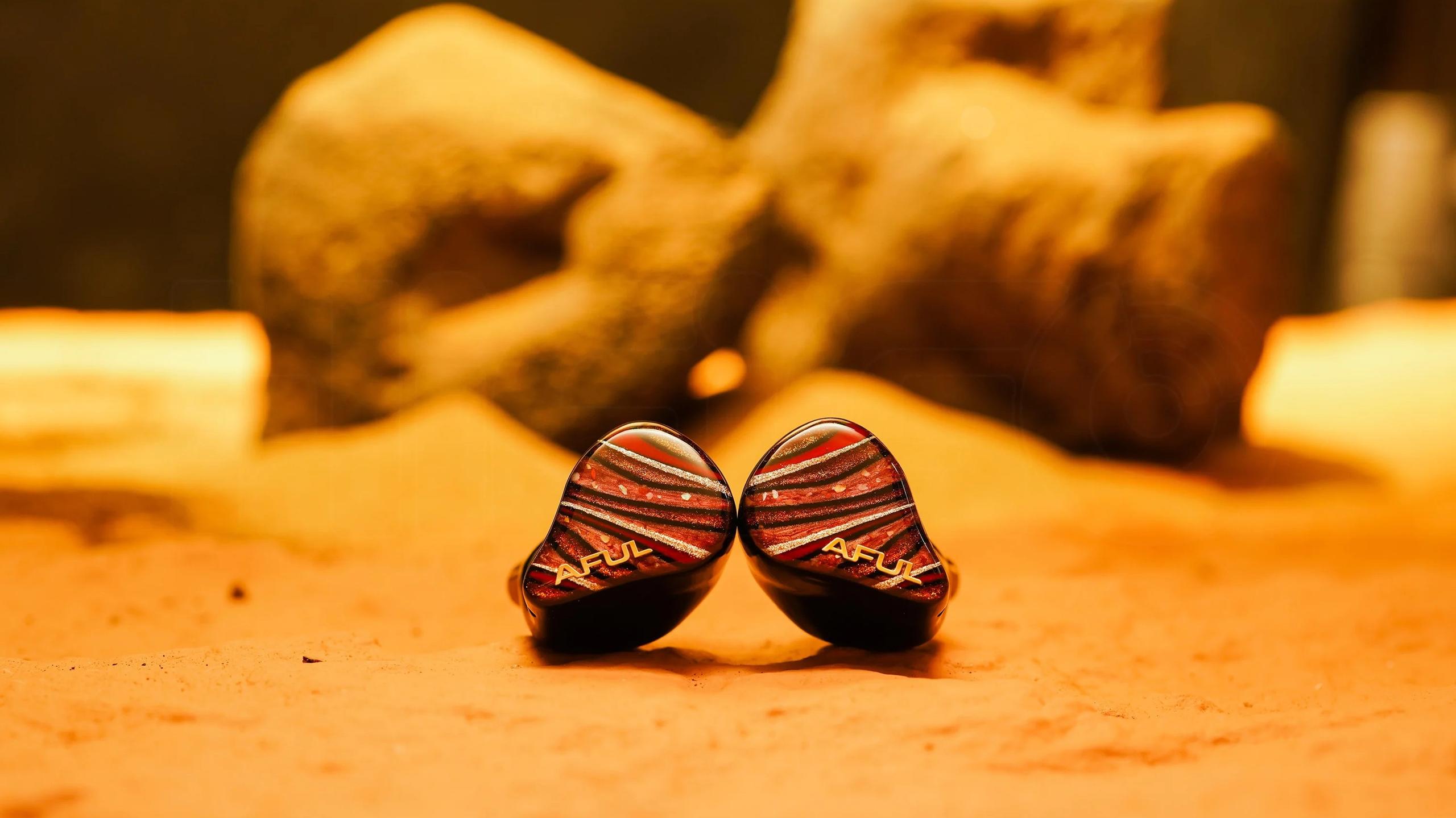 AFUL Performer 8S in-ear monitors with Jupiter-inspired faceplates on a warm-toned surface.
